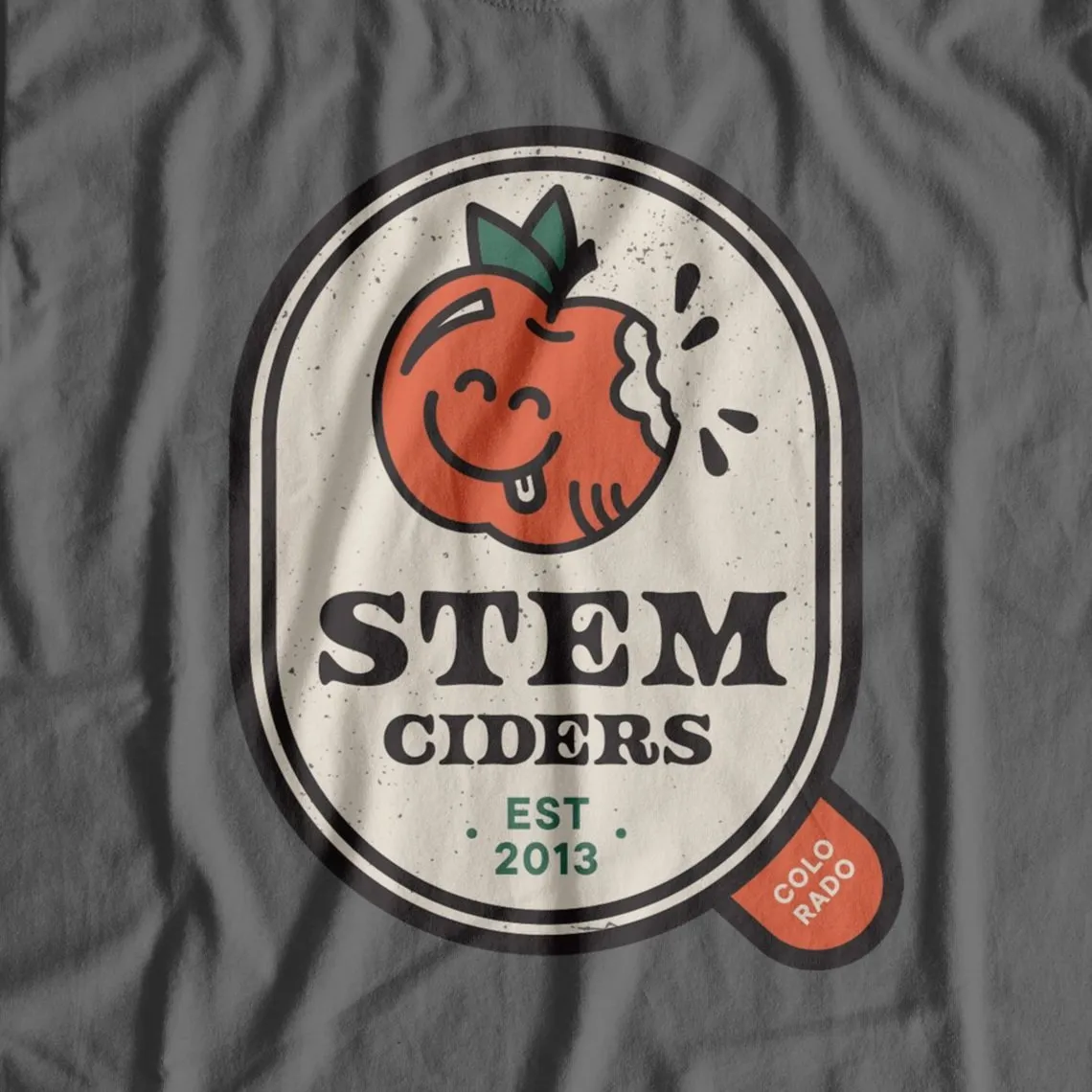 Gray t-shirt with a Stem Ciders apple badge graphic