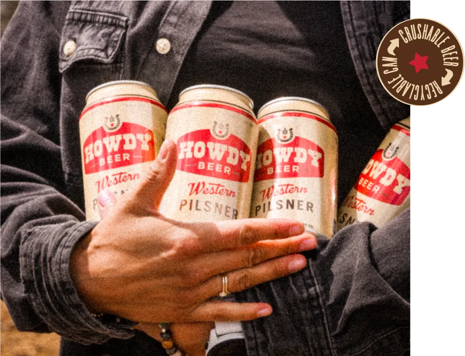 Person in a denim jacket cradling an armful of Howdy cans