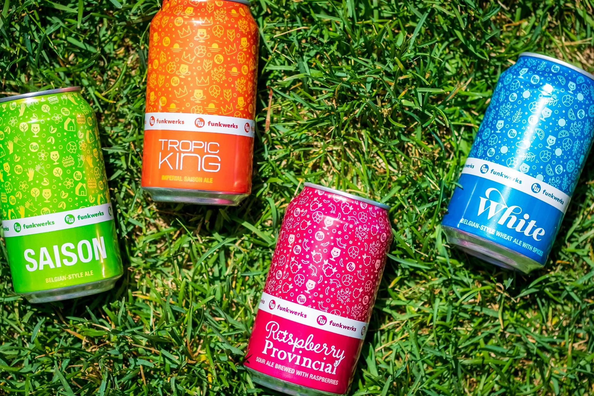 Saison, Tropic King, and Raspberry Provincial cans lying in grass