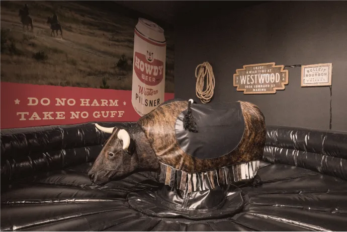 Mechanical bull in front of a Howdy-branded wall mockup