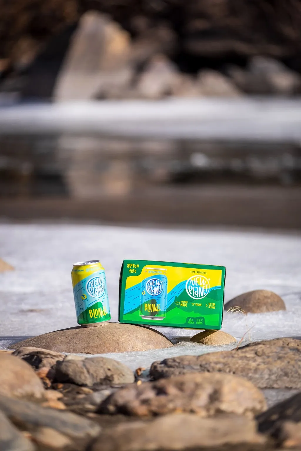 Blonde can and 6-pack on river rocks