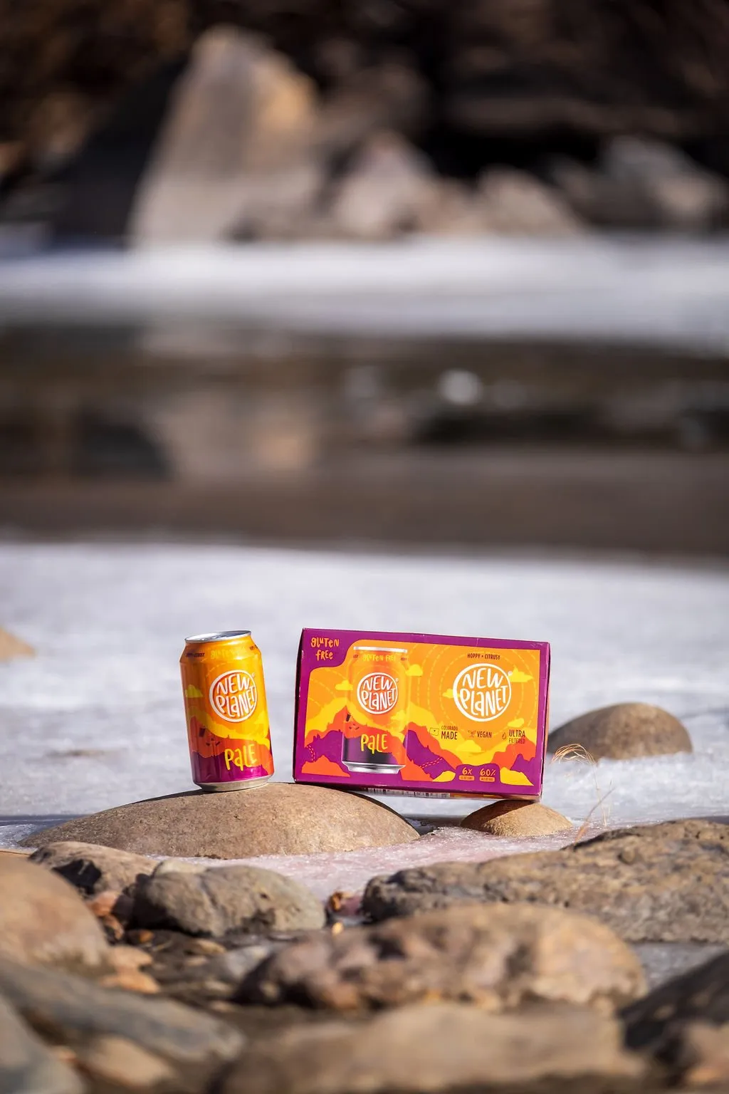 Pale can and 6-pack on river rocks