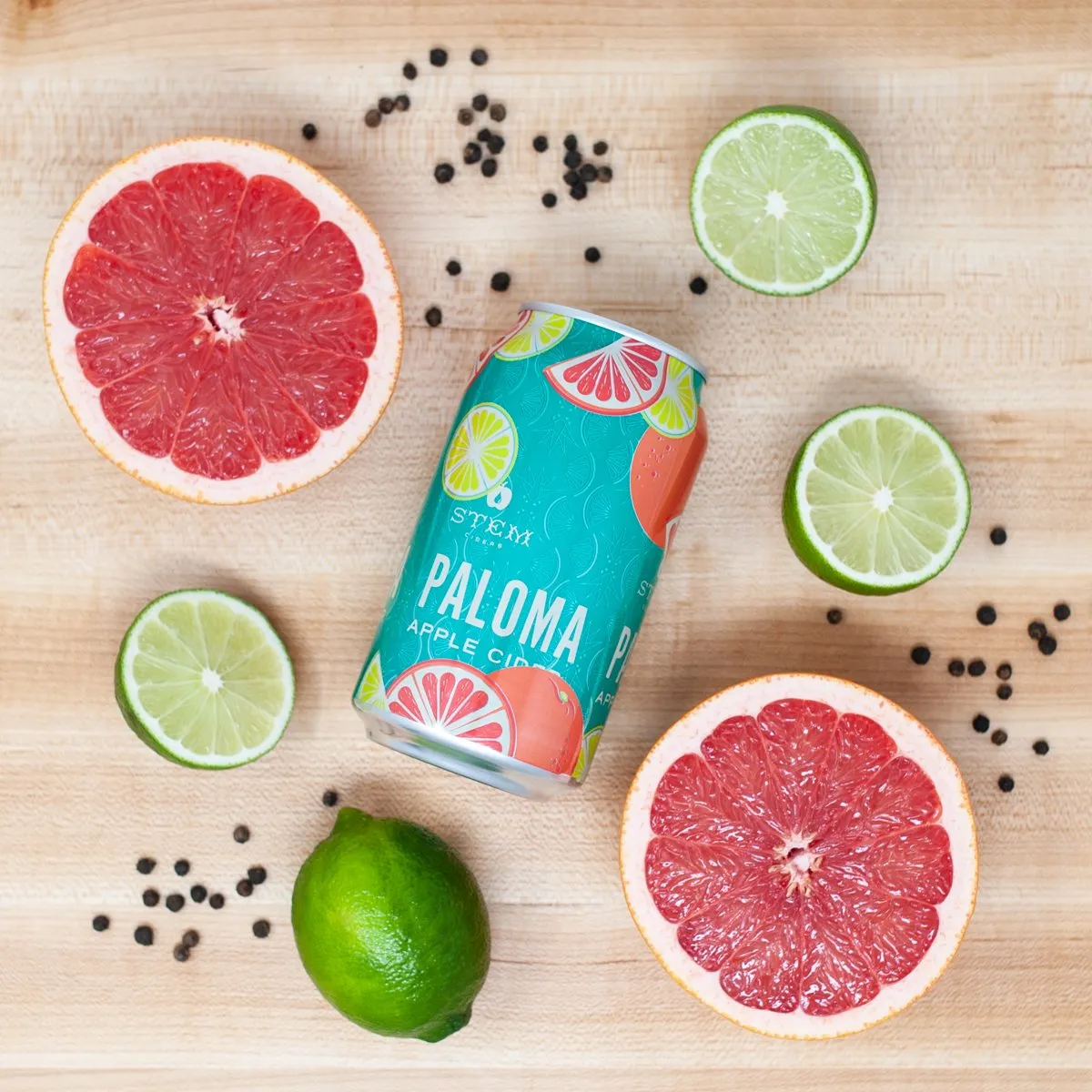 Paloma can flat lay with grapefruit halves, limes, and peppercorns