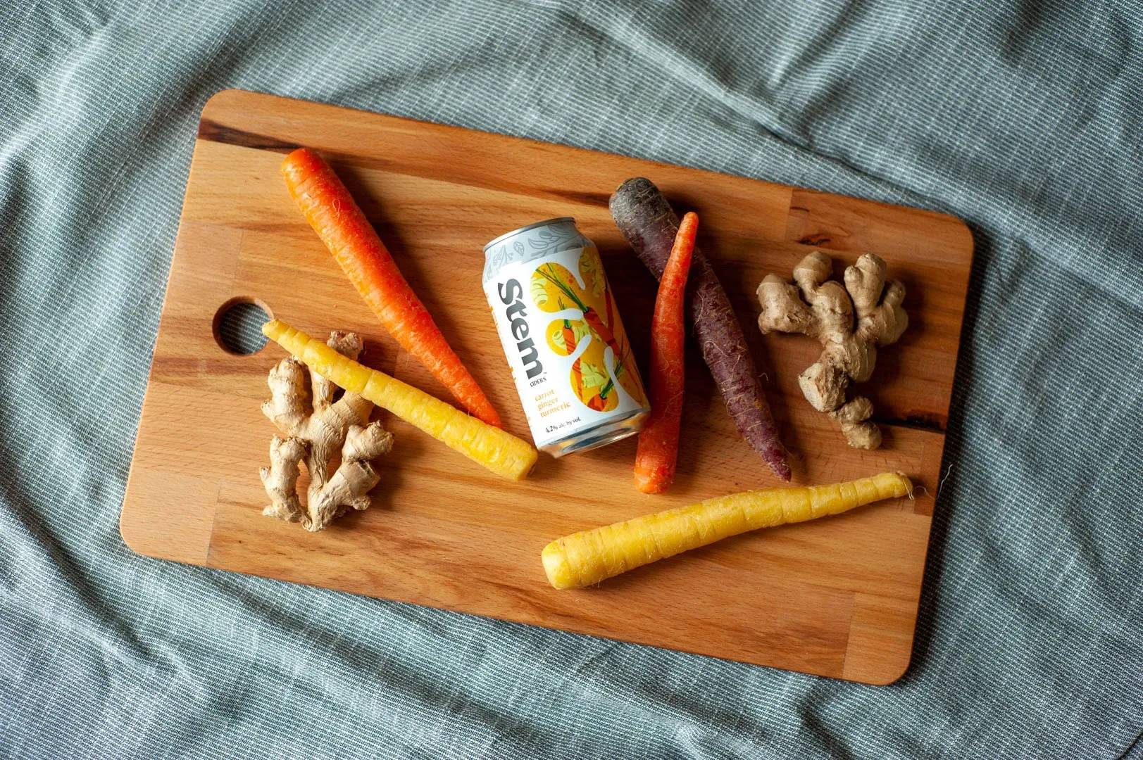 Carrot Ginger Turmeric can on a cutting board with carrots and ginger